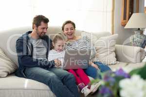 Parents and daughter using laptop