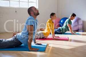instructor with students practicing cobra pose in health club