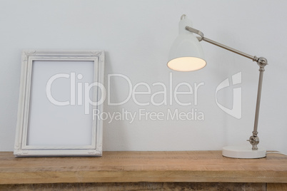 Picture frame and illuminated lamp on table