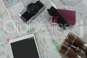 Passport, camera, binoculars and digital tablet on map