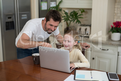 Father and daughter working on laptop