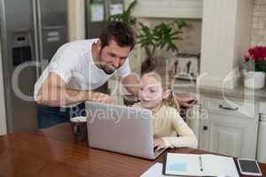 Father and daughter working on laptop