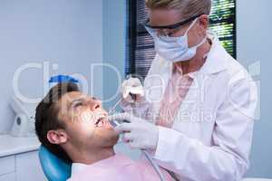 Dentist holding medical equipment while giving treatment to patient