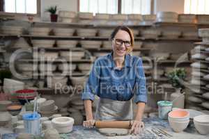 Portrait of female potter flattening the clay with rolling pin