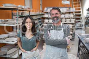 Male and female potter standing in pottery workshop