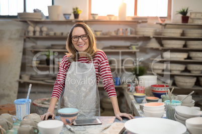 Portrait of female potter standing at worktop