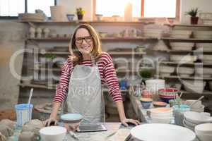 Portrait of female potter standing at worktop