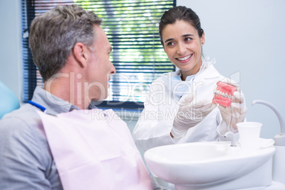 Dentist showing dental mold to man at clinic