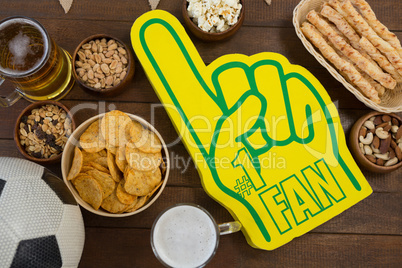 Foam hand, snacks and football on wooden table