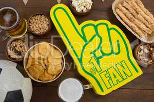 Foam hand, snacks and football on wooden table