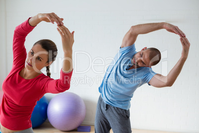 Female student with instructor exercising in yoga studio