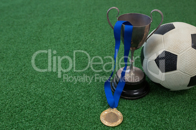 Football, trophy and medal on artificial grass