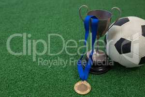 Football, trophy and medal on artificial grass