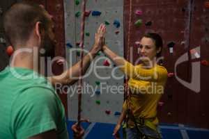 Athletes giving high five while standing by climbing wall