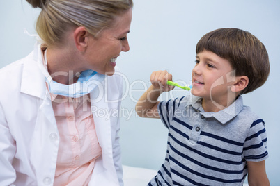 Boy holding toothbrush while looking at dentist