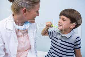 Boy holding toothbrush while looking at dentist
