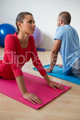Student with instructor doing cobra pose in health club
