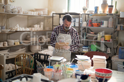 Male potter maintaining record on clipboard