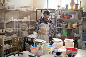 Male potter maintaining record on clipboard