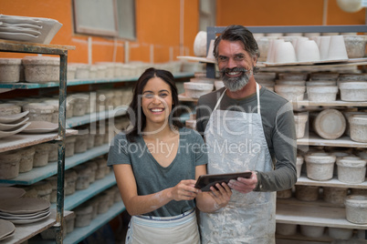 Portrait of male and female potter holding digital tablet