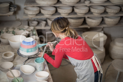 Female potter painting bowl