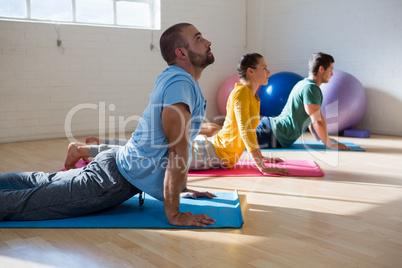 Instructor with students practicing cobra pose in yoga studio