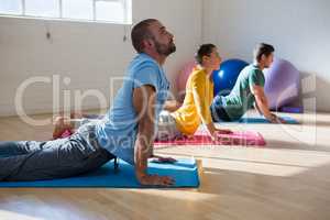 Instructor with students practicing cobra pose in yoga studio