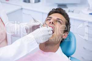 Dentist holding medical equipment while giving treatment to man