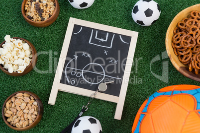 Strategy board, whistle and football on artificial grass