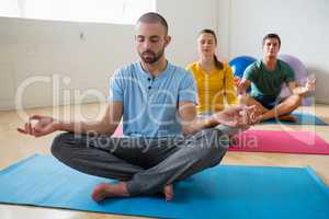 Yoga instructor with students meditating at club