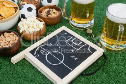 Strategy board, football and snacks on artificial grass