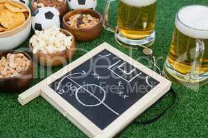 Strategy board, football and snacks on artificial grass