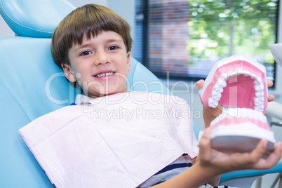 Boy holding dental mould while sitting on chair at medical clinic