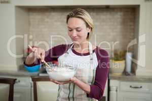 Smiling woman mixing eggs and wheat flour