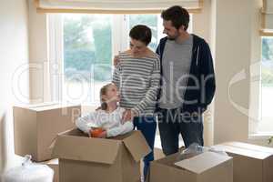 Parents and daughter opening cardboard boxes in living room