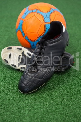 Football and cleats on artificial grass