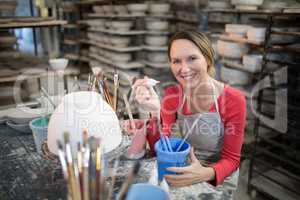 Portrait of female potter holding color tube