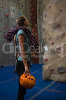 Athlete with rope and sports helmet looking at climbing wall in club