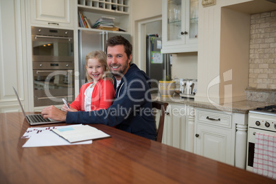 Father and daughter working on laptop at home