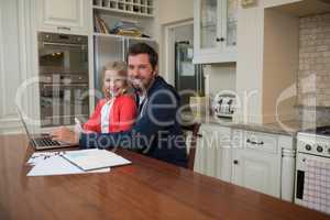 Father and daughter working on laptop at home