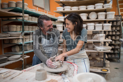 Male potter assisting female potter