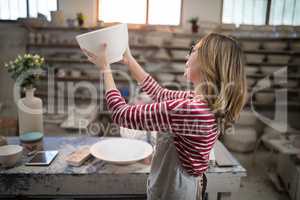 Female potter checking bowl