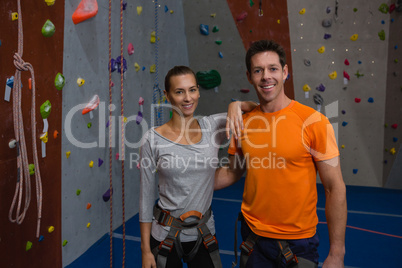 Portrait of confident athletes standing by climbing wall in gym