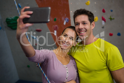 Woman taking selfie with male athlete through mobile phone in club