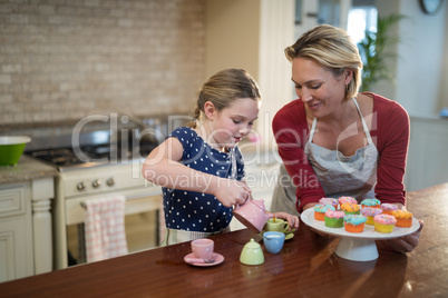 Mother and daughter pouring tea in the cups