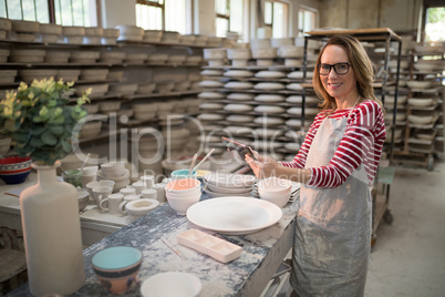 Portrait of female potter using digital tablet