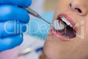 Dentist holding angled mirror by woman at medical clinic