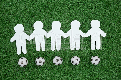 Paper cut outs and footballs arranged on artificial grass