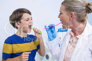 Dentist and boy brushing teeth against wall
