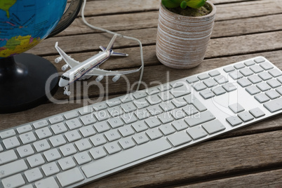 Pot plant, globe, keyboard and airplane model on wooden plank